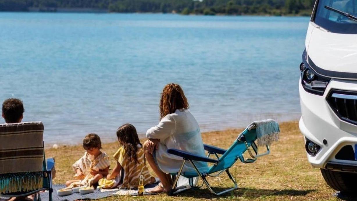 4 personen die bij een camper zitten